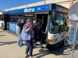 Tres ancianos saludan a la cámara mientras suben a un autobús del metro de Madison en un soleado día de otoño.